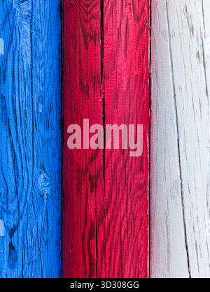 Detail of the grain, knots, and cracks in multicolored wood, highlighted by the sun. Colors of the french flag. Stock Photo