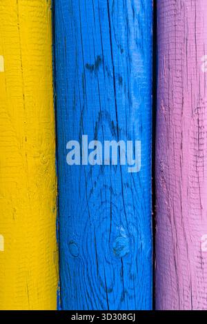 Detail of the grain, knots, and cracks in multicolored wood, highlighted by the sun. Stock Photo