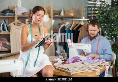 Young fashion designers sketching and sewing in clothing studio Stock Photo