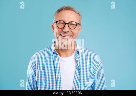 Smiling Mature Man in Glasses Posing in a Studio With Blue Background Stock Photo
