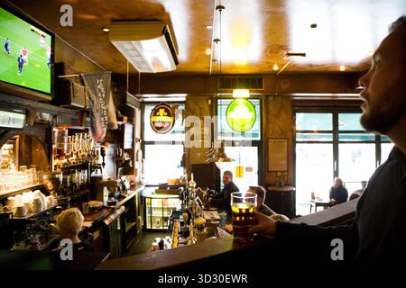 Man drinking beer and watching a soccer match.  The Dubliners, Stroget, Copenhagen, Denmark. Stock Photo