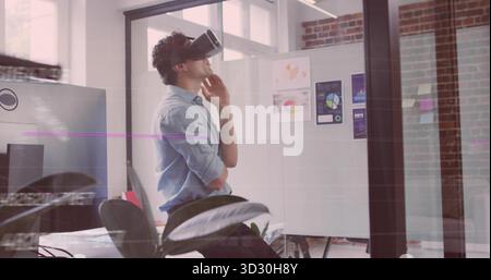 Leaning back man wearing VR headset interacting in modern office, with charts and monitors Stock Photo