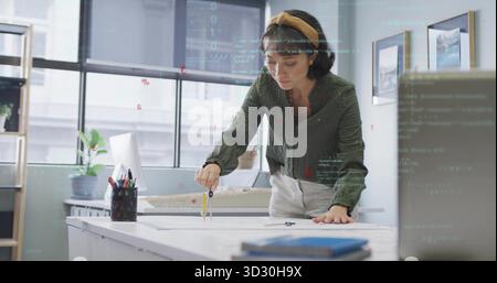 Designer drawing on blueprint with metal compass at design studio, including scale model Stock Photo