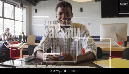Typing African American man working at open office desk, with computer, smartphone and sticky notes Stock Photo