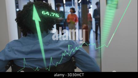Facing man in wheelchair wearing blue shirt looking down office corridor, with stock chart overlay Stock Photo