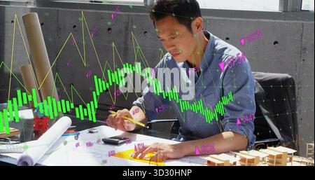 Asian man analyzing candlestick chart in design office, with blueprints on worktable, copy space Stock Photo