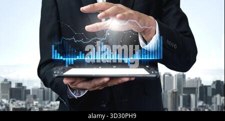 A businessman interacts with a high-tech tablet displaying dynamic financial graphs against an urban skyline, illustrating modern data analysis for pr Stock Photo