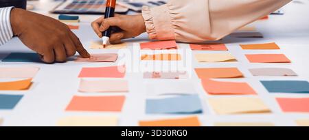 Two hands engage with colorful sticky notes on a table, showcasing a vibrant brainstorming session in a collaborative workspace to generate innovative Stock Photo