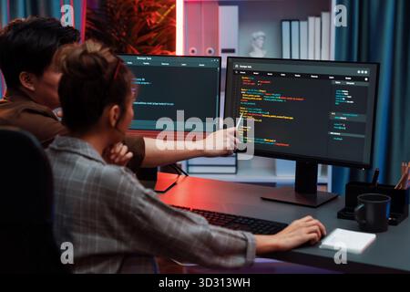 Smart IT developer looking at coding program application on computer screen of online website at back side, analyzing intelligent database system deve Stock Photo