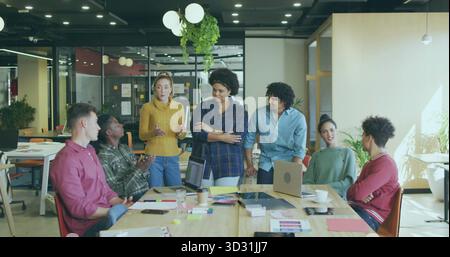 Seven office professionals collaborating around conference table in office, with laptops Stock Photo