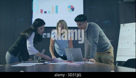 Collaborating three colleagues analyzing sales in boardroom, with laptop computer, monitor display Stock Photo