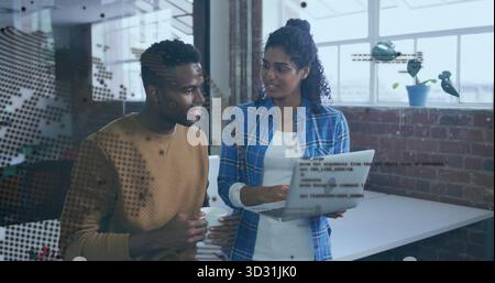 Discussing code snippets while software developers viewing laptop at brick office, with coffee mug Stock Photo