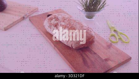 Crusty loaf of bread resting on wooden cutting board at kitchen counter, with steel knife, scissors Stock Photo