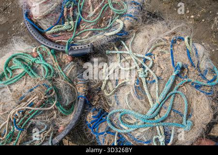 Close-up overhead view of a tangled pile of old, dirty fishing nets, ropes, and lines on the ground Stock Photo