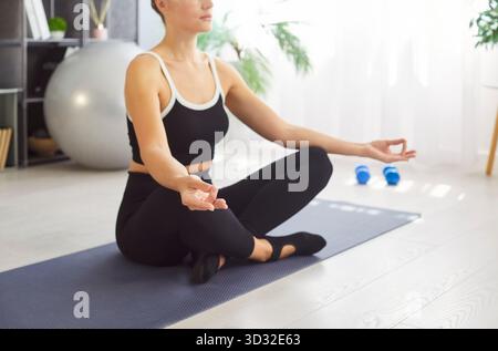 Close-up of woman practicing seated meditation on a textured yoga mat at home Stock Photo