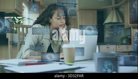 Analyzing data on laptop, woman in home kitchen with notebooks pen coffee cup and water bottle Stock Photo