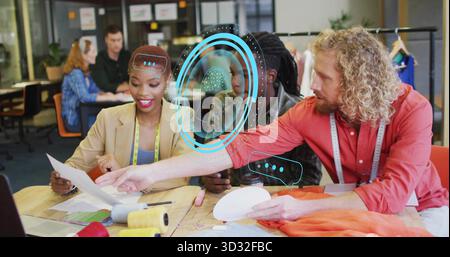 Three designers holding patterns and sorting fabric swatches in fashion studio with measuring tapes Stock Photo