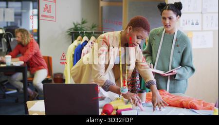 Collaborating two fashion designers examining fabric in fashion design studio with thread spools Stock Photo
