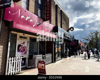Manchester, UK - September 29, 2025: Busy Manchester street with pink massage parlor storefronts and pedestrians. Stock Photo