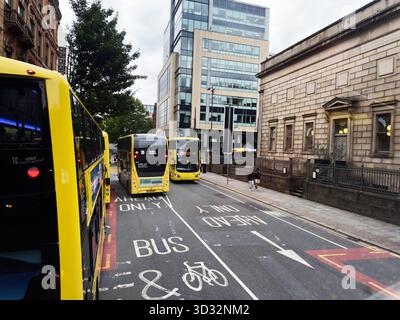 Manchester, UK - September 29, 2025: Busy Manchester street with yellow buses, pedestrians, and modern architecture. Stock Photo