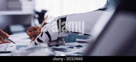 An innovative scene depicting human hands collaborating with a robotic hand in a contemporary office setting, focusing on data analysis for effective Stock Photo