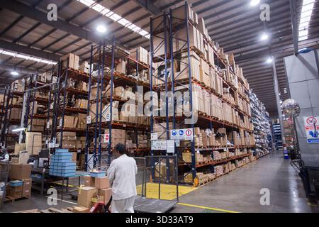 Men at work, wearing protective stuff, handling boxes in a warehouse Stock Photo