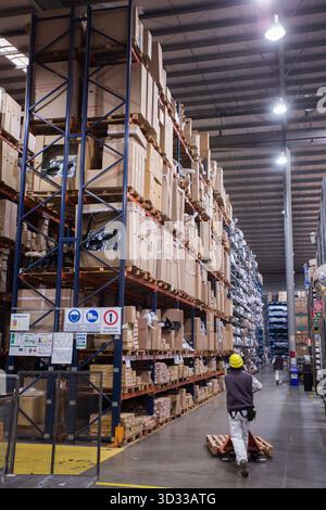 Men at work, wearing protective stuff, handling boxes in a warehouse Stock Photo