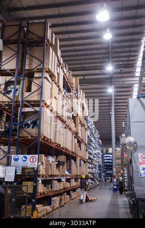 Men at work, wearing protective stuff, handling boxes in a warehouse Stock Photo