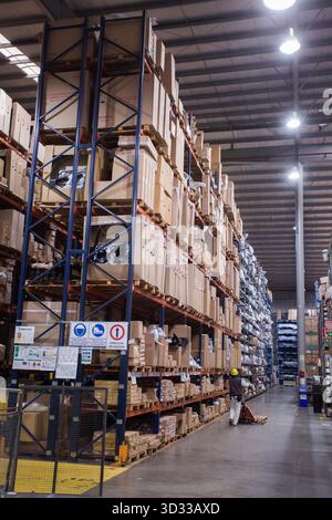 Men at work, wearing protective stuff, handling boxes in a warehouse Stock Photo