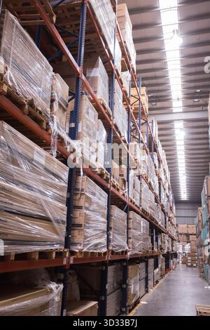 Men at work, wearing protective stuff, handling boxes in a warehouse Stock Photo