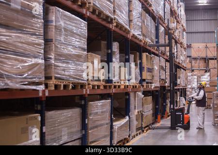 Men at work, wearing protective stuff, handling boxes in a warehouse Stock Photo