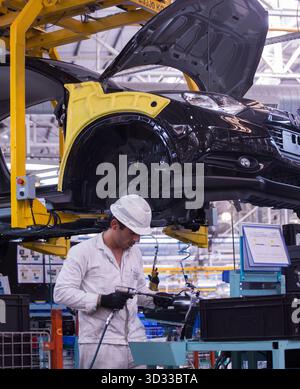 Men at work. Young man wearing protective stuff, working with tools and machinery in a car factory Stock Photo