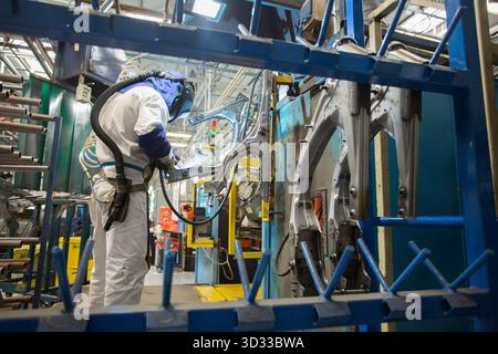 Men at work. Young man wearing protective stuff, working with tools and machinery in a car factory Stock Photo