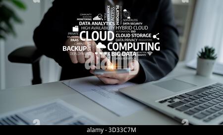 A businessman interacts with cloud computing concepts and data analytics using a smartphone and laptop, surrounded by modern infographics in an office Stock Photo