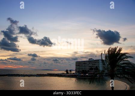Coastal resort with palm trees and modern beachfront hotel at twilight with dramatic clouds over sea at can pastilla mallorca balaeric isles spain Stock Photo