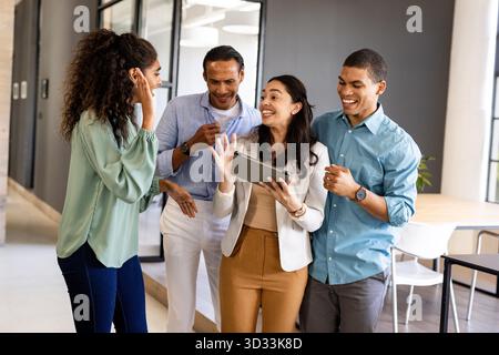 Business team collaborating and laughing while using tablet in modern office. Collaboration, teamwork, digital, technology, brainstorming, professional || Model released Stock Photo