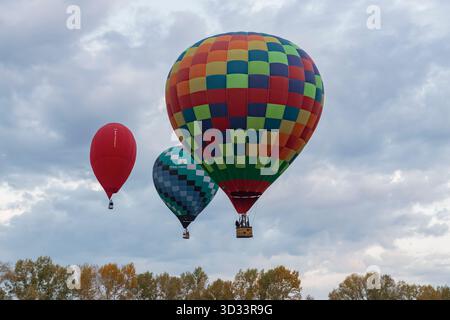 BELOKURIKHA, RUSSIA - SEPTEMBER 19, 2025: Three air balloons fly over the trees on a early September morning Stock Photo