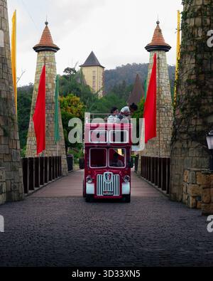 Colmar Tropicale, Bukit Tinggi, Pahang, Malaysia - April 10, 2025 - The red sightseeing bus framed by castle-style towers and colourful flags. Stock Photo