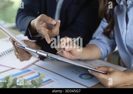 Close-up of professionals engaged in a detailed financial discussion, analyzing charts and documents for insights Stock Photo
