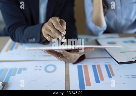 Two business professionals analyze financial reports and charts, engaged in a productive discussion to drive insights Stock Photo