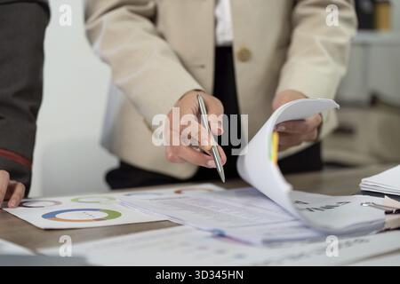 Two business professionals engage in a collaborative discussion over project documents, showcasing teamwork and communication in a modern office Stock Photo