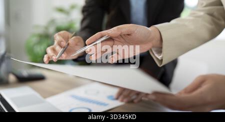 Two professionals collaborating on project strategies, sharing insights and ideas while reviewing important documents in a modern office Stock Photo