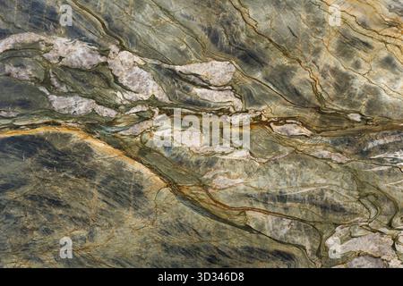 Elegant quartzite surface with vibrant green, golden, and cream tones, featuring unique veining Stock Photo
