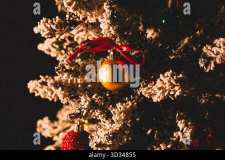 Close-up of golden Christmas bauble ornament hanging on Christmas tree branch on dark background Stock Photo