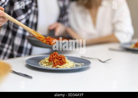 Unrecognizable couple having breakfast in kitchenn, man serving dinner, woman sitting at table at home in domestic kitchenn Stock Photo