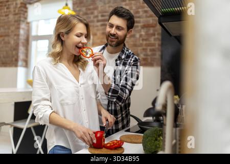 Happy couple cooking dinner together in kitchenn at home preparing vegetable salad for breakfast Stock Photo
