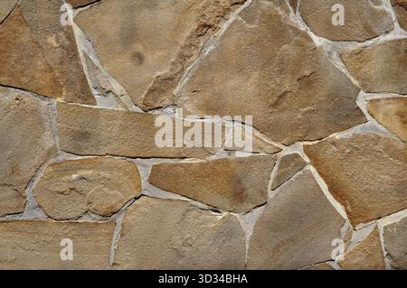 Yellow stone limestone texture, irregular shape and natural lines. Retaining wall Stock Photo