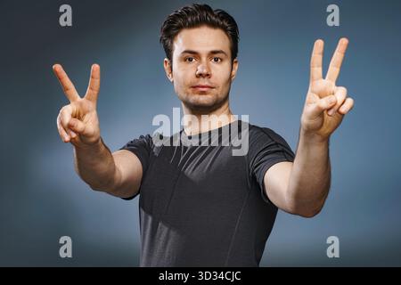 Young brunette man showing victory handsign Stock Photo