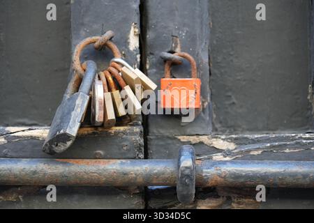 Rusty locks on a black metal gate, one with a heart Stock Photo