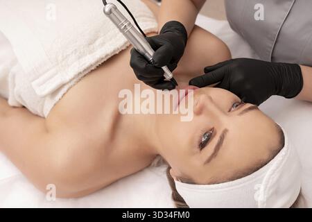 Cosmetologist applying permanent make up on the lips Stock Photo